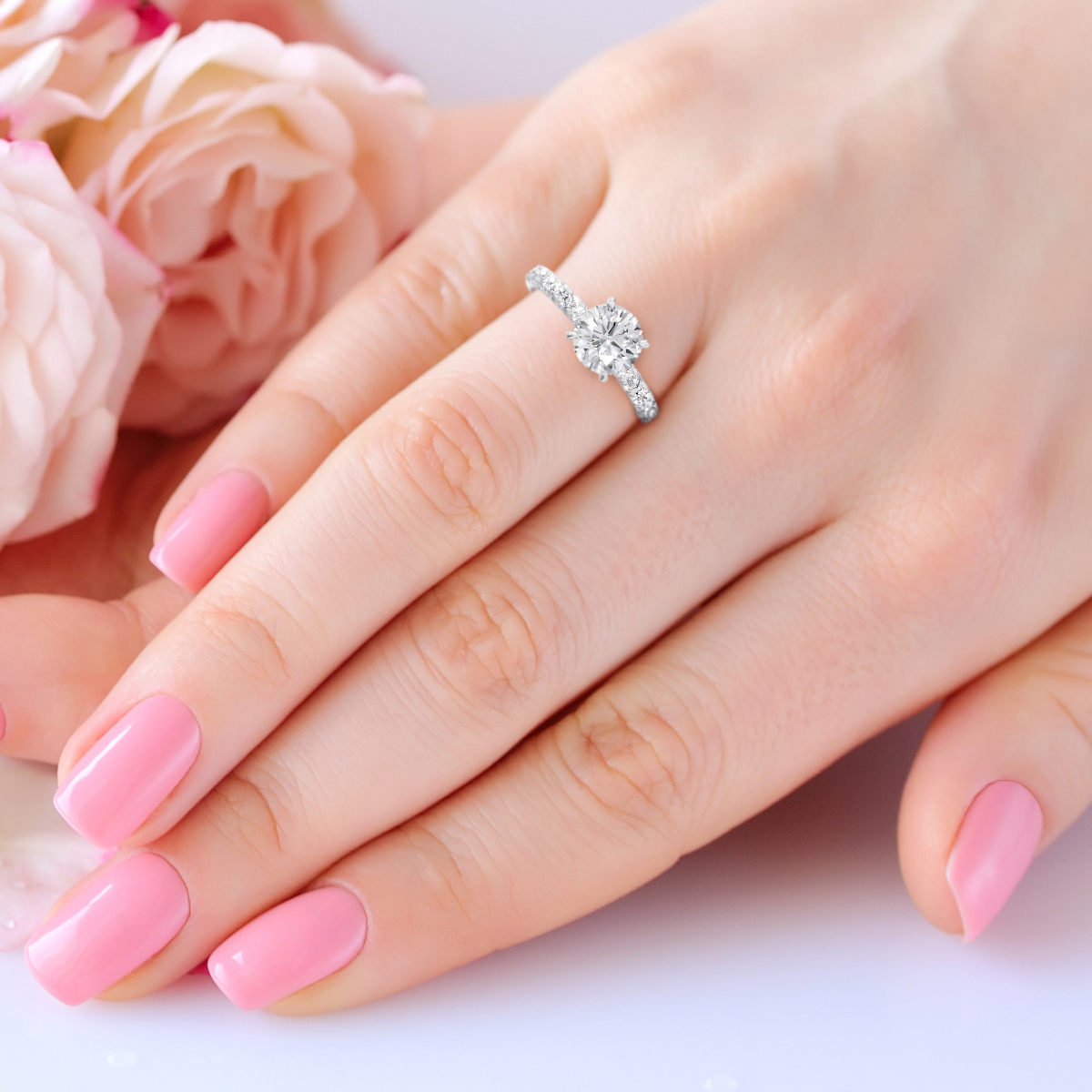 Hands of a woman with pink manicure on nails and roses against white background